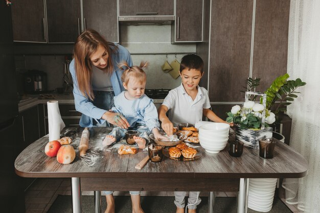 Foto glückliche familie in der küche. mama und kinder bereiten teig vor und backen einen kuchen für den muttertag.