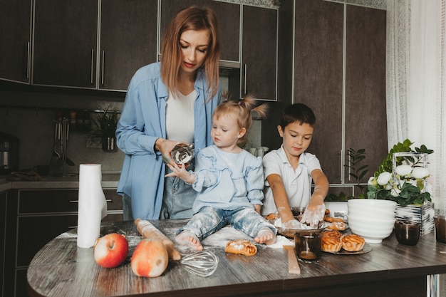 Glückliche Familie in der Küche. Mama und Kinder bereiten Teig vor und backen einen Kuchen für den Muttertag.