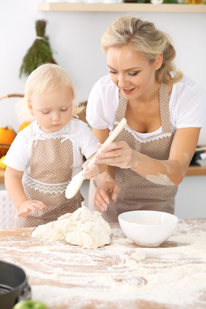 Glückliche Familie in der Küche. Mutter und Kind Tochter kochen Feiertagstorte oder Kekse für den Muttertag, lässige Lifestyle-Fotoserie im realen Interieur