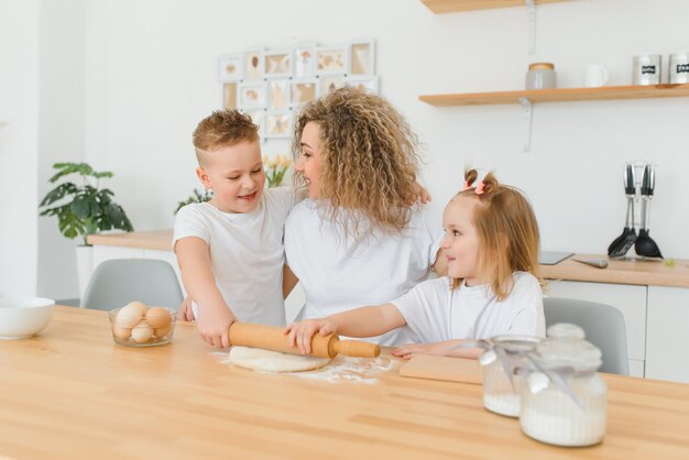 Glückliche Familie in der Küche. Mutter und Kinder bereiten den Teig zu, backen Kekse