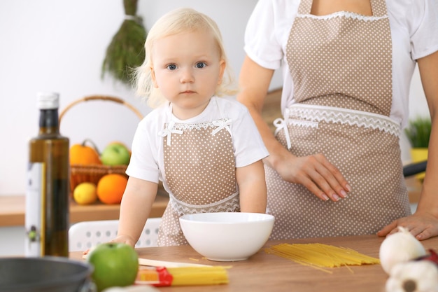 Glückliche Familie in der Küche. Mutter- und Kindertochter, die leckeres Frühstück kocht