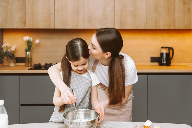 Glückliche Familie in der Küche Mutter und Tochter bereiten Teig zu, backen Kekse Osterkuchen