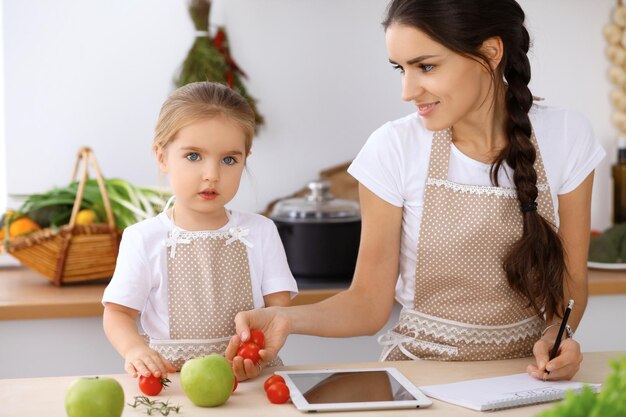 Glückliche Familie in der Küche Mutter und Tochter machen Menüs zum Kochen leckeres Frühstück in der Küche Kleiner Helfer ist bereit für den Haushalt