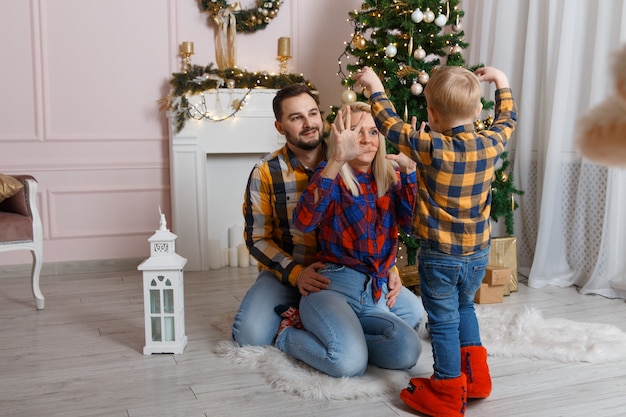 Glückliche Familie in der Nähe von Weihnachtsbaum, die Spaß auf dem Boden hat.