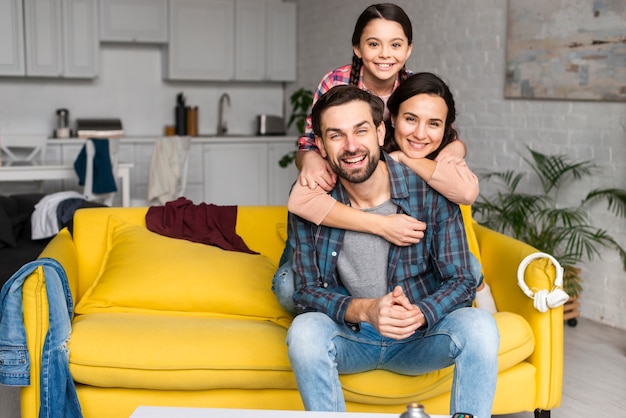Glückliche familie in einem haufen und vater, die auf sofa sitzen