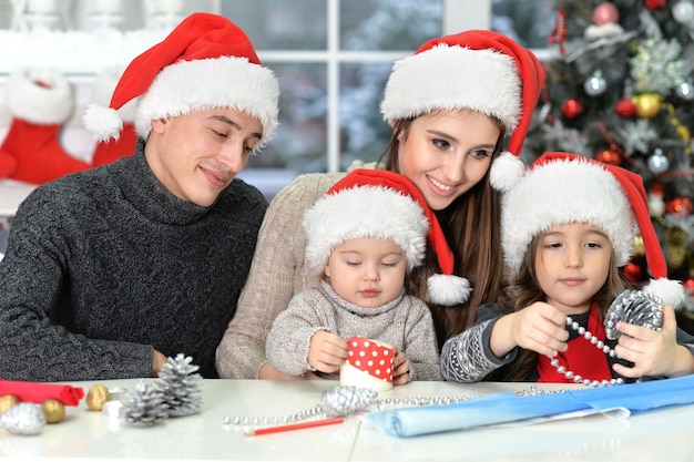 Glückliche Familie in Weihnachtsmützen, die sich auf Weihnachten vorbereiten