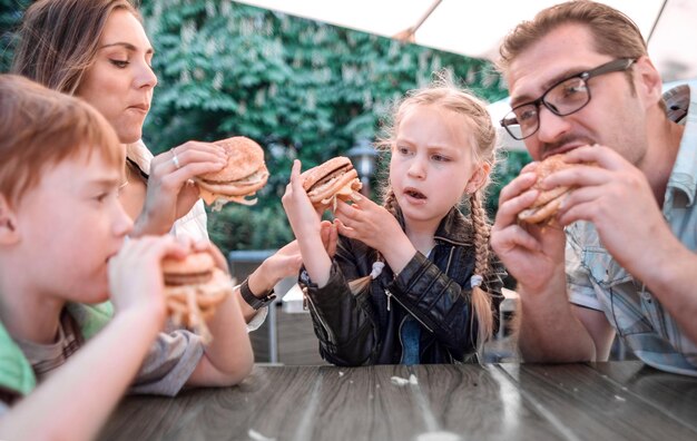 Foto glückliche familie isst burger an einem tisch in einem café