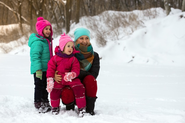 Glückliche Familie - lächelnde Mutter und kleine Töchter am Wintertag