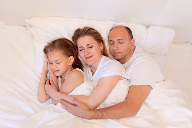 Glückliche Familie, Mama, Papa, Tochter schlafen im Bett im Schlafzimmer zu Hause