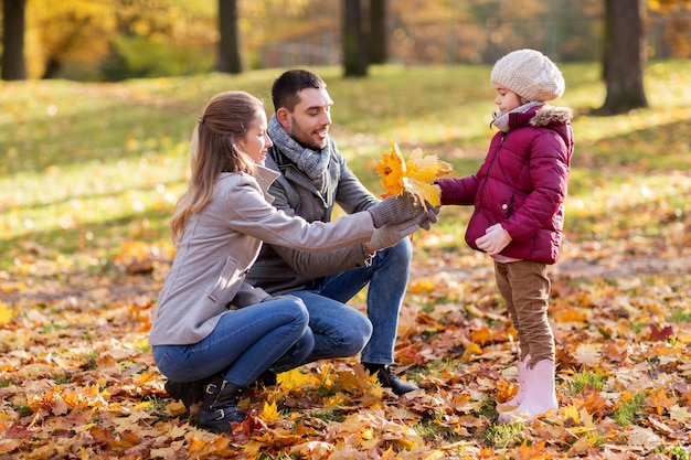 Foto glückliche familie mit ahornblättern im herbstpark