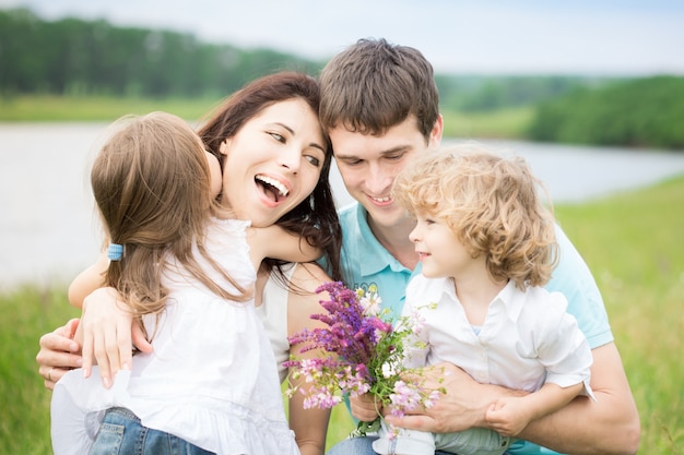 Glückliche Familie mit Blumen, die sich im Frühlingsfeld im Freien amüsieren