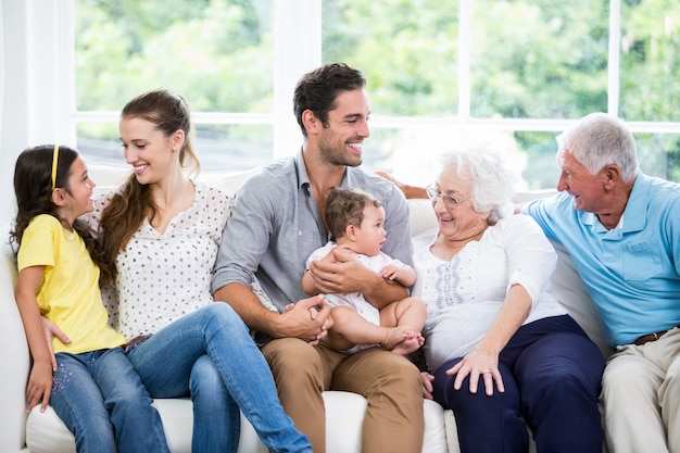 Glückliche Familie mit den Großeltern, die auf Sofa sitzen