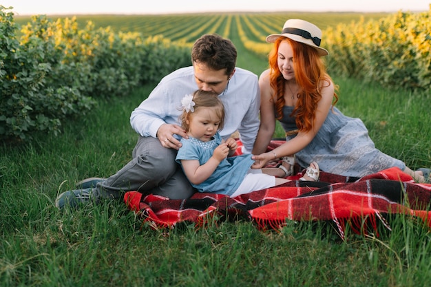 Glückliche Familie mit der kleinen Tochter, die Zeit zusammen im sonnigen Feld verbringt