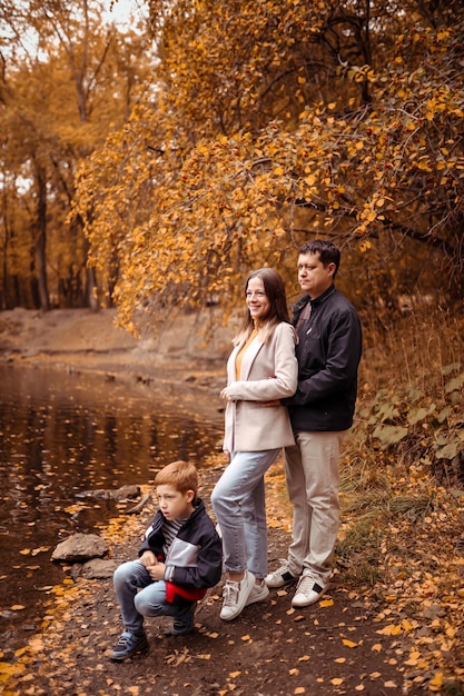 Glückliche Familie mit einem Kind auf einem Herbstspaziergang in einem Stadtpark mit einem See, der Enten füttert Familienspaß