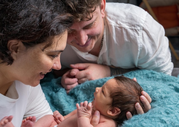 Glückliche Familie mit einem neugeborenen Baby. Mama und Papa schauen das Baby zärtlich an