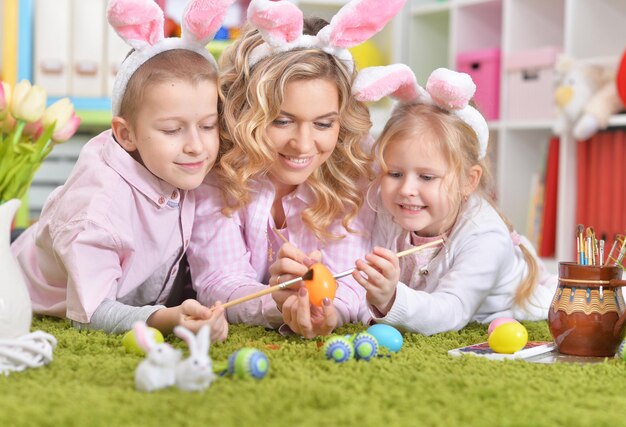 Glückliche Familie mit Hasenohren, die sich auf Ostern vorbereiten und Eier färben