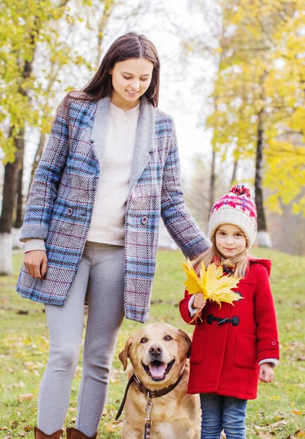 Glückliche Familie mit Hund im sonnigen Herbstpark