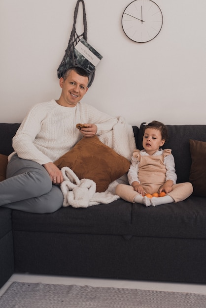 Glückliche Familie mit Kind feiert Neujahr und Weihnachten am geschmückten Weihnachtsbaum und Garlan