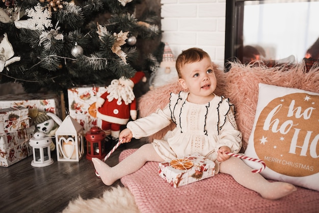 Glückliche Familie mit Kind feiert Neujahr und Weihnachten am geschmückten Weihnachtsbaum und Girlanden