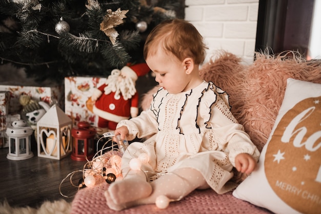 Glückliche Familie mit Kind feiert Neujahr und Weihnachten am geschmückten Weihnachtsbaum und Girlanden