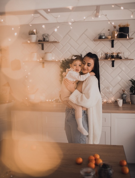 Glückliche Familie mit Kind feiert Neujahr und Weihnachten am geschmückten Weihnachtsbaum und Girlanden