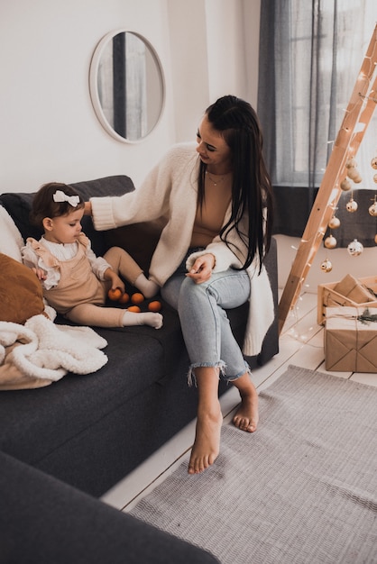 Glückliche Familie mit Kind feiert Neujahr und Weihnachten am geschmückten Weihnachtsbaum und Girlanden