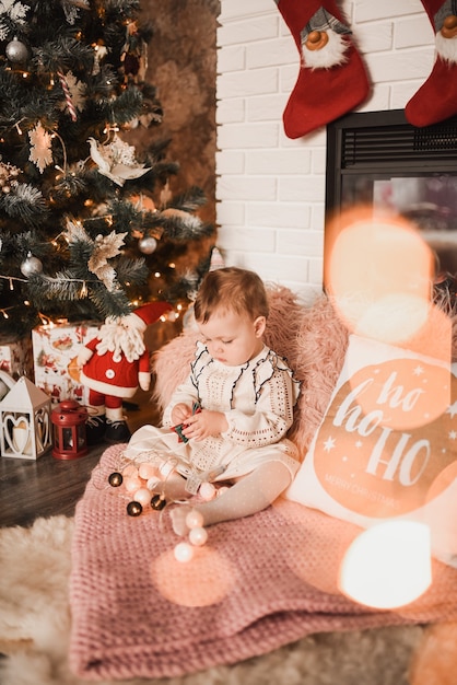 Glückliche Familie mit Kind feiert Neujahr und Weihnachten am geschmückten Weihnachtsbaum und Girlanden