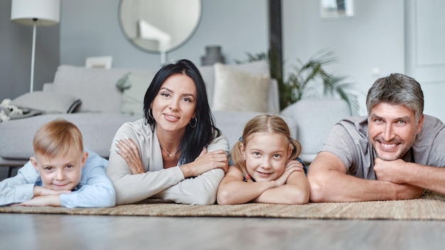 Glückliche Familie mit Kindern, die im Wohnzimmer auf dem Boden liegen