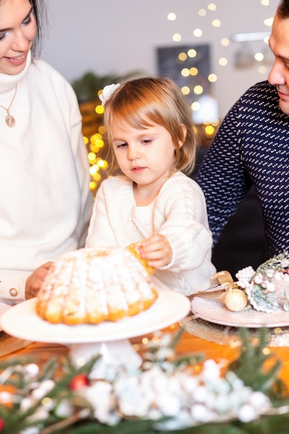 Glückliche Familie mit Kindern, die Teig in der Weihnachtsküche rollen.