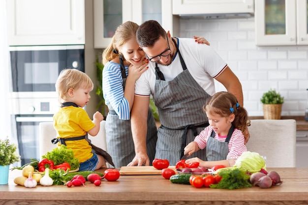 Glückliche Familie mit Kindern, die zu Hause Gemüsesalat zubereiten