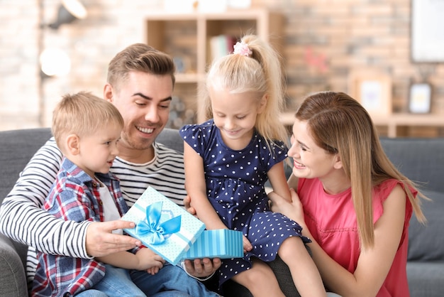 Glückliche Familie mit kleinen Kindern, die zu Hause eine Geschenkbox öffnen