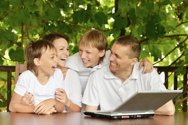 Glückliche Familie mit Laptop im Sommer