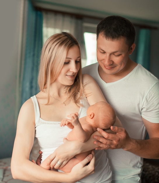 Glückliche Familie mit neugeborenem Baby, das in ihrer Wohnung steht.