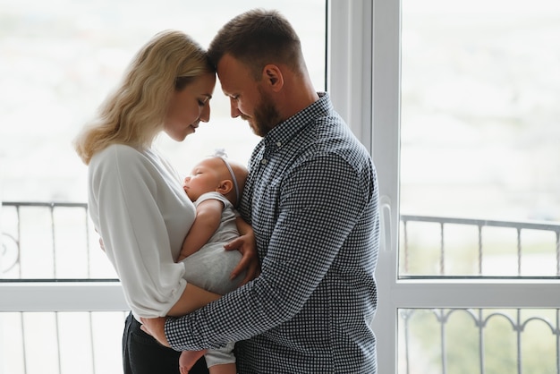 Glückliche Familie mit neugeborenem Baby durch das Fenster