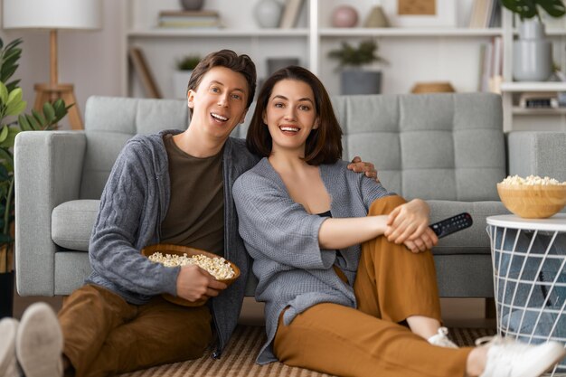 Glückliche Familie mit Popcorn sitzt zu Hause auf dem Sofa Paar verbringt Zeit zusammen