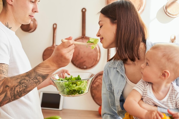 Glückliche Familie mit Sohn in der Küche, die gemeinsam das Frühstück zubereitet