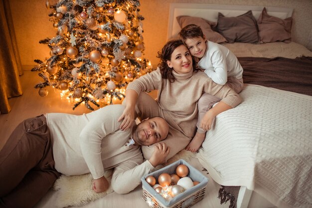 glückliche Familie mit Sohn unter Weihnachtsbaum im Schlafzimmer