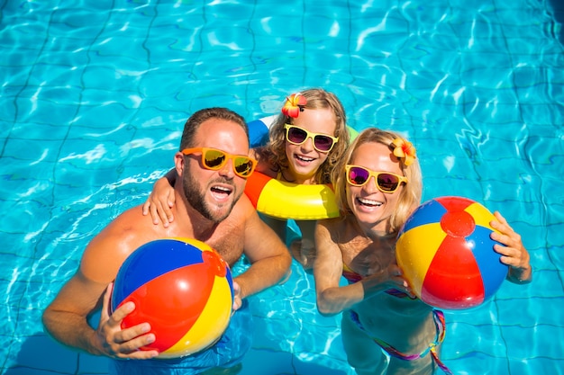 Glückliche Familie mit Sonnenbrille und Blumen im Haar mit bunten Hüpfburgen im Pool in