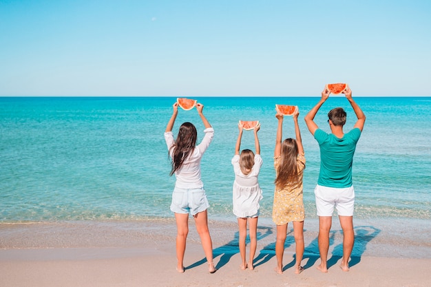 Glückliche Familie mit Wassermelone am Strand. Eltern und Kinder am Meer haben Spaß.