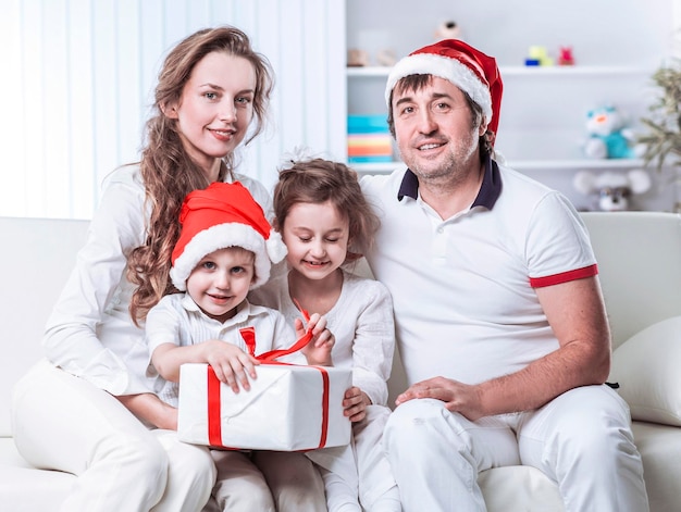 Glückliche Familie mit Weihnachtsgeschenk auf einem Sofa im Kinderzimmer sitzend