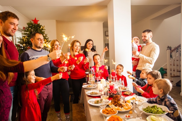 Glückliche Familie mit Wunderkerzen, die sich bei der Dinnerparty zu Hause amüsieren. Feier der Weihnachtsferien