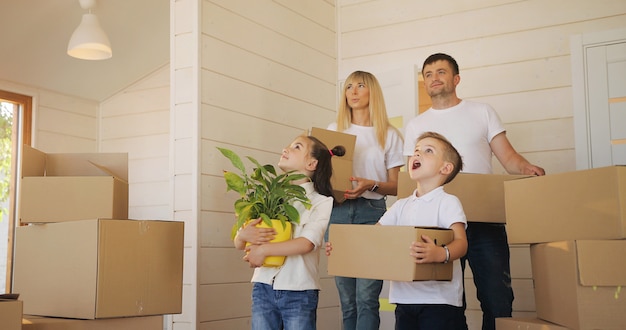 Glückliche Familie mit zwei Kindern am neuen Haus, das Kästen hält