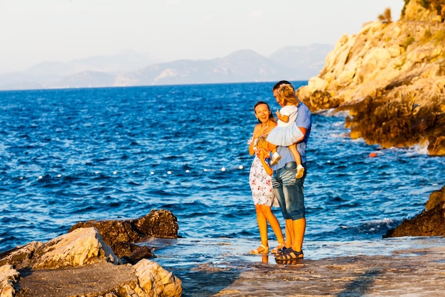 glückliche familie mit zwei kindern geht am meer spazieren und schaut auf meereswellen