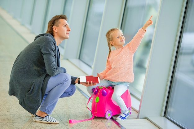 Glückliche Familie mit zwei Kindern im Flughafen viel Spaß beim Warten auf das Einsteigen