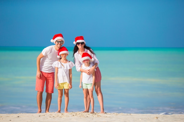 Glückliche Familie mit zwei Kindern in Santa Hat in den Sommerferien