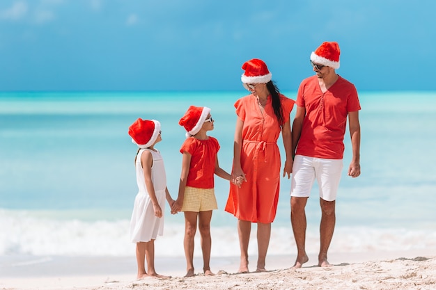 Glückliche Familie mit zwei Kindern in Santa Hat in den Sommerferien