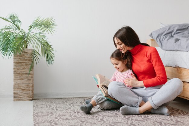 Glückliche Familie Mutter und Kind Tochter lesen Halten Buch im Bett liegen