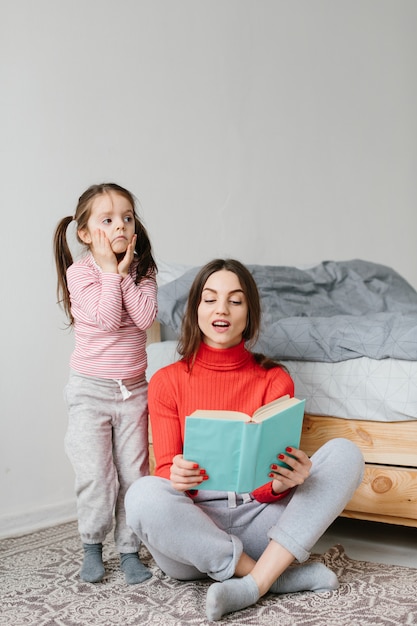 Glückliche Familie Mutter und Kind Tochter lesen Halten Buch im Bett liegen