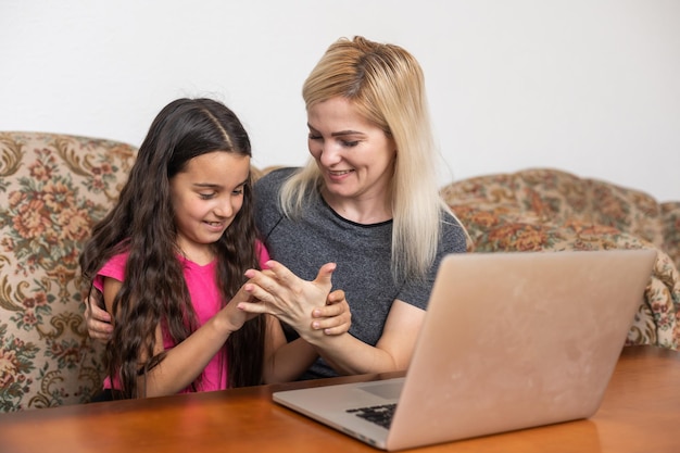 Glückliche Familie Mutter und Tochter, die Videounterhaltung mit Laptop-Computertechnologie im Wohnzimmer ansehen, genießen das Leben zu Hause