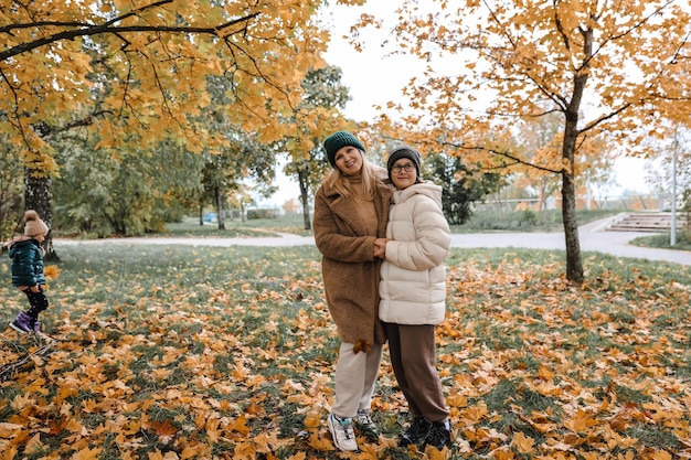 Glückliche Familie Mutter und Tochter ist im Herbst Stadtpark Sie posieren lächelnd spielen und Spaß haben Leuchtend gelbe Bäume